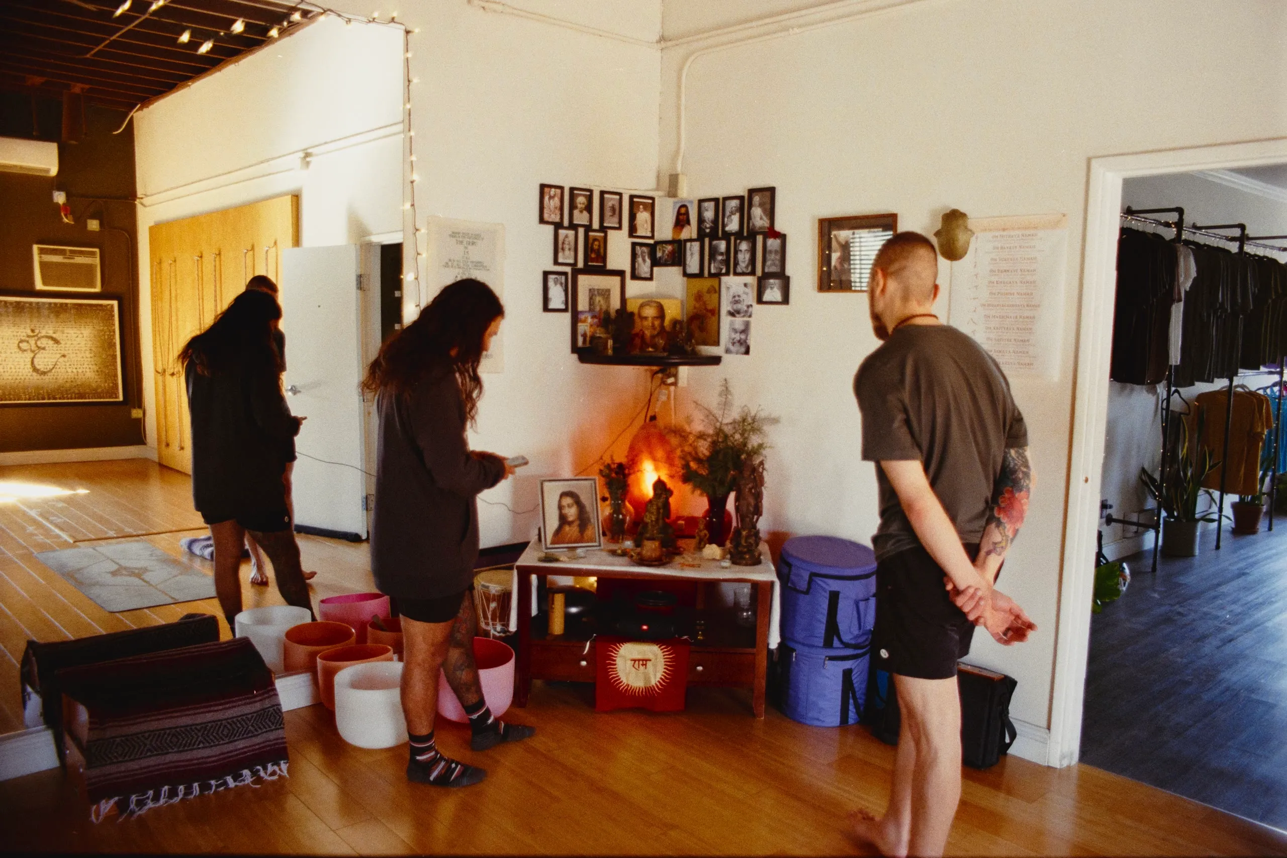 A sunlit studio with framed pictures, a candlelit altar and singing bowls on the floor